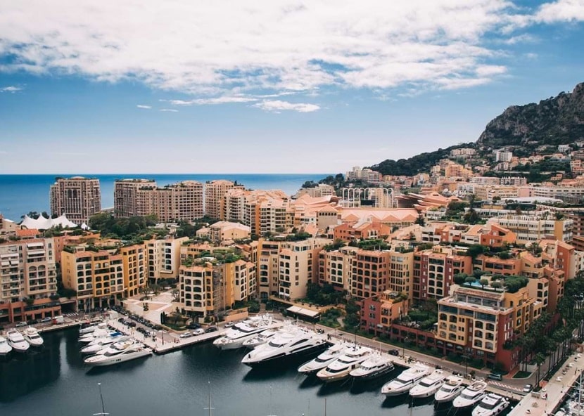 CDATA[Monaco consente ai cittadini stranieri di diventare residenti legali attraverso la Carte de Séjour (permesso di soggiorno). Il processo richiede di dimostrare autosufficienza finanziaria, disporre di un alloggio e superare verifiche sui precedenti. Questa guida copre tutto ciò che devi sapere per ottenere la residenza a Monaco.
Tipi di Carta di Soggiorno a Monaco
Il Principato rilascia quattro categorie di permessi di soggiorno:
Carte de Séjour Temporaire (Temporanea)
Validità: 1 anno, rinnovabile annualmente fino a 3 anni.
Tassa di rilascio: €80 | Rinnovo: €40
Carte de Séjour Ordinaire (Ordinaria)
Validità: 3 anni, rinnovabile.
Idoneità: Dopo 3 anni di residenza continua.
Tassa di rilascio: €100 | Rinnovo: €50
Carte de Séjour Privilégiée (Privilegiata)
Validità: 10 anni, rinnovabile indefinitamente.
Idoneità: Dopo 10 anni di residenza con presenza effettiva.
Tassa di rilascio: €160 | Rinnovo: €80
Carte Conjoint de Monégasque (Coniuge di Monegasco)
Per i coniugi stranieri di cittadini monegaschi.
Requisiti per la Residenza a Monaco
Tutti i richiedenti devono soddisfare questi requisiti fondamentali:
Alloggio a Monaco
Devi avere un indirizzo registrato nel Principato, tramite acquisto di un immobile, affitto (contratto minimo di 12 mesi) o vivendo con un coniuge o parente stretto già residente. L’alloggio deve essere adeguato al numero di membri della famiglia che presentano domanda.
Autosufficienza finanziaria
Una banca monegasca deve confermare che disponi di fondi sufficienti per mantenerti. In pratica, le banche richiedono generalmente depositi a partire da €500.000, anche se l’importo esatto varia a seconda dell’istituto e del profilo del richiedente.
Fedina penale pulita
Devi fornire un certificato del casellario giudiziale di tutti i paesi in cui hai risieduto negli ultimi cinque anni. Il certificato deve essere stato rilasciato da meno di 3 mesi al momento della domanda.
Per i cittadini non UE/SEE
Devi prima ottenere un visto di lungo soggiorno francese (Tipo D) presso l’ambasciata o il consolato francese nel tuo paese di residenza prima di richiedere la residenza a Monaco.
![Requisiti per la residenza a Monaco